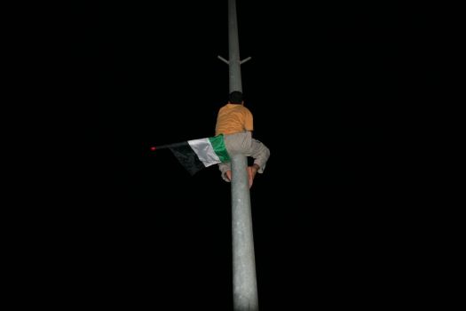 palestinian climbs pole to fly flag