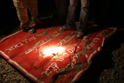 Palestinians stand on warning sign